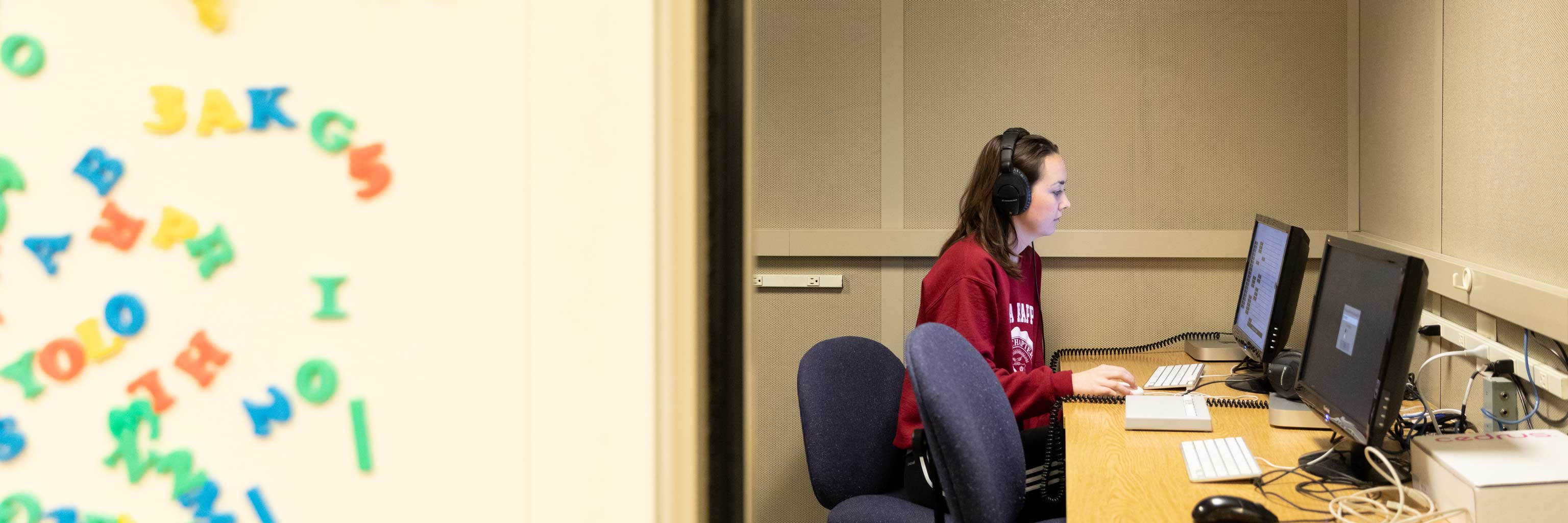 Student sitting at a computer with headphones on